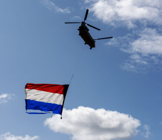 Gigantische Nederlandse vlag onder militair vliegtuig vanuit Noordwijk naar Zandvoort voor F1 race
