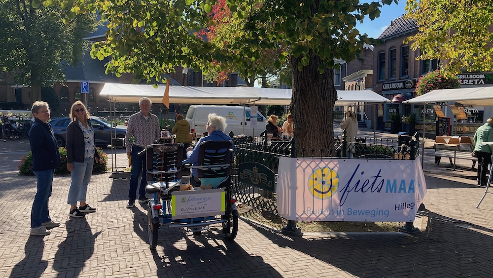 Bollenmarkt2024 duofiets met gast en vrijwilligers bij kraampjes